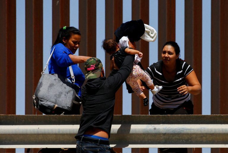 Nachdem sie die Grenze über den Rio Grande überquert haben, heben Asylsuchende bei El Paso, Texas, ein Kind über eine Abgrenzung. Reuters