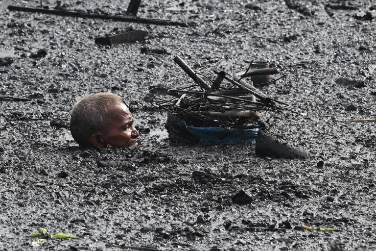 Ein Mann sucht im Flutwasser in Manila nach recycelbaren Materialien, nachdem ein Feuer zahlreiche Häuser zerstörte. afp