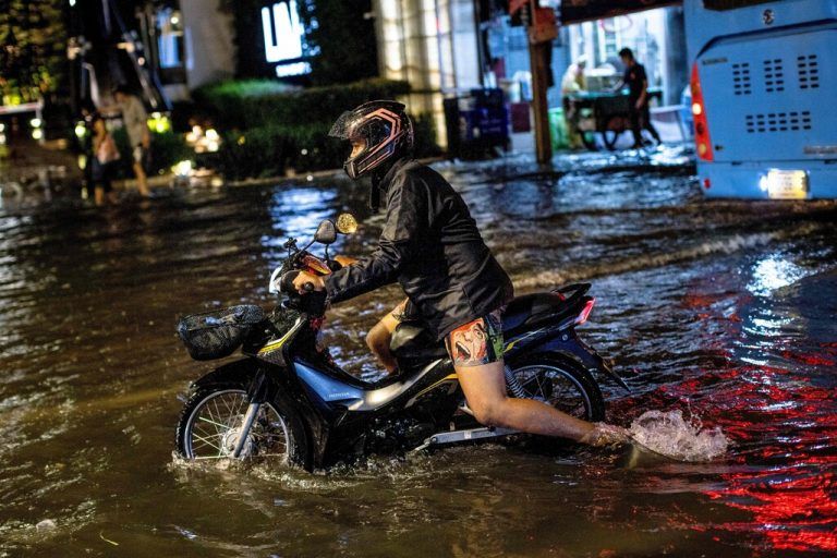Ein Mann watet mit seinem Moped durch eine überflutete Straße nach Starkregen in Bangkok, Thailand. AFP