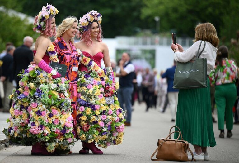 Eine Besucherin posiert für ein Foto mit Frauen in Blumenkleidern auf der Chelsea Flower Show in London. Die Gartenschau findet alljährlich auf dem Gelände des Royal Hospital statt. AFP