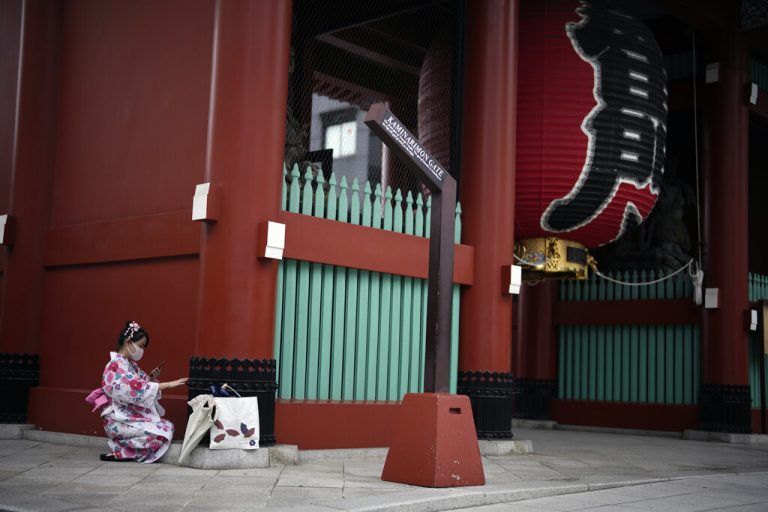 Eine Frau im traditionellen Kimono hält auf einer Einkaufsstraße im Stadtteil Asakusa in Tokio kurz inne, um ein Selfie zu knipsen. AP