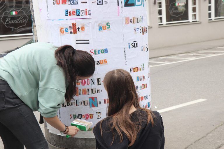 Mit Kleister werden die Plakate an der Saumarkt-Säule angebracht.