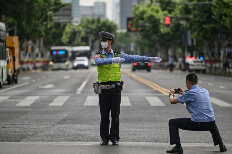 Nachdem der Lockdown in Shanghai größtenteils aufgehoben wurde, fotografiert ein Polizist einen Kollegen, der den Verkehr kontrolliert. AFP