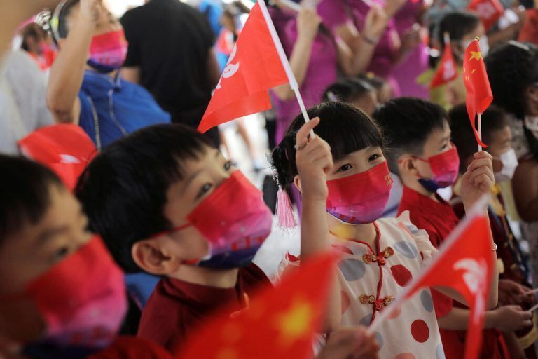 Kinder singen und schwenken Fahnen aus China und Hongkong.