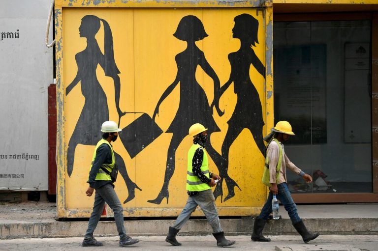 Auf einer Straße in Phnom Penh, der Hauptstadt Kambodschas, passieren Bauarbeiter ein Wandbildnis. AFP