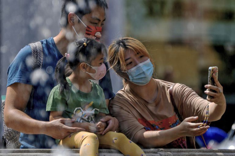 Masken-Selfie: Eine Familie fotografiert sich bei einem Einkaufszentrum in der chinesischen Hauptstadt Peking mit dem Smartphone. AFP