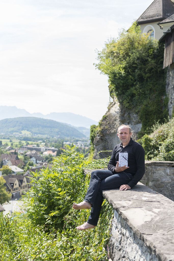 Der Vorarlberger Schriftsteller vor der Basilika Rankweil mit seinem Buch „Vor hundert Jahren und einem Sommer“. 
              
              Johannes Fink