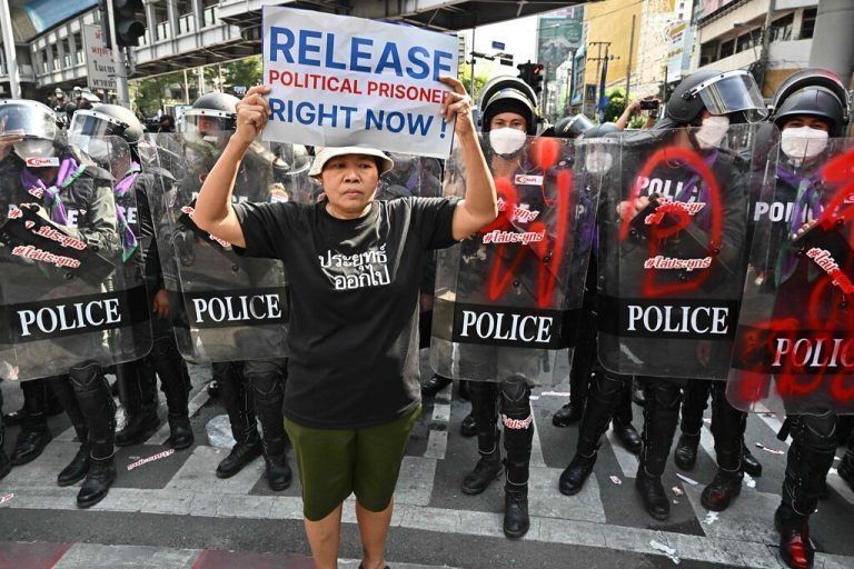 Ein Demonstrant hält beim Gipfel der Asiatisch-Pazifischen Wirtschaftskooperation (APEC) in Bangkok ein Schild vor der Bereitschaftspolizei hoch. AFP