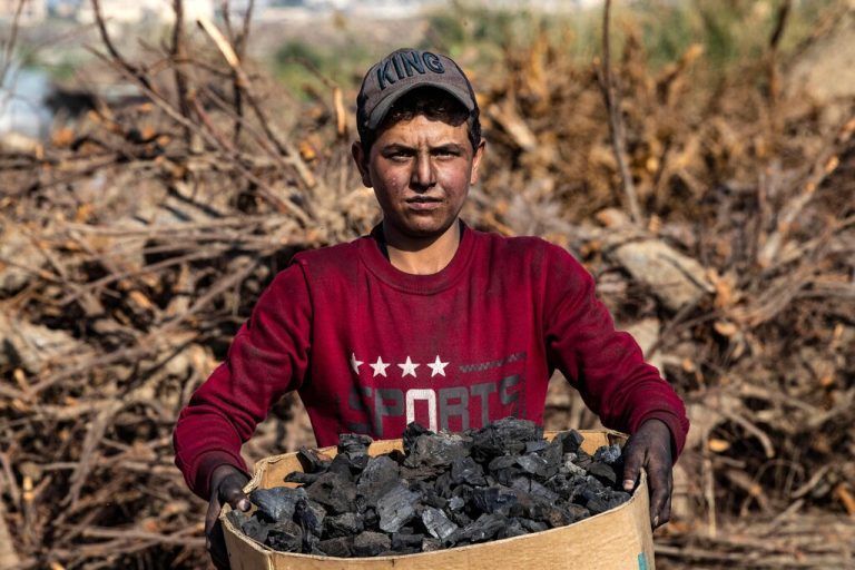 Ein syrischer Arbeiter trägt in der nordsyrischen Stadt Raqa eine Kiste mit Holzkohle. AFP