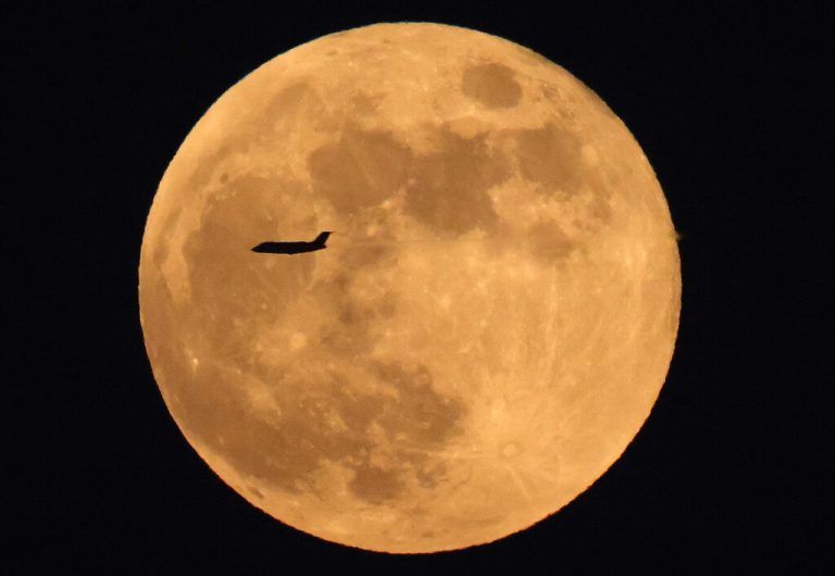Ein Verkehrsflugzeug fliegt vor dem riesigen aufgehenden Vollmond über Kuwait-Stadt. AFP