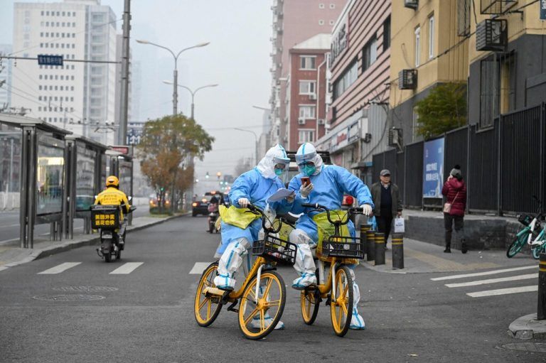 Gesundheitspersonal in Schutzausrüstung (PSA), kontrolliert die Corona-schutzmaßnahmen in einer Straße in Peking. AFP