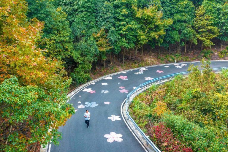 In Ningbo in der chinesischen Provinz Zhejiang joggt eine Frau über eine Straße, die mit Blumen verziert ist. AFP