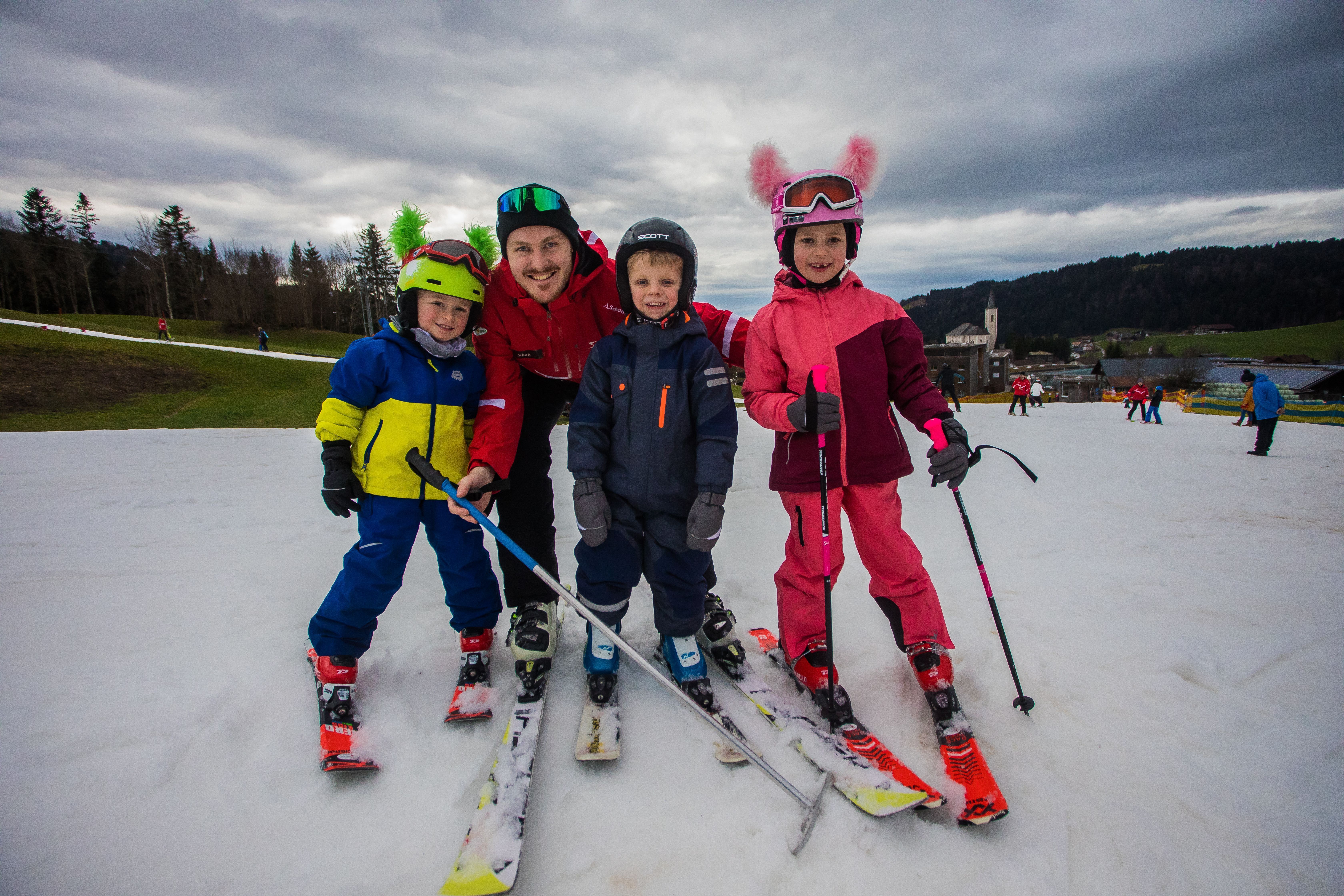 Anton (4), Theo (5) und Ida (6) haben Spaß mit Skilehrer Noah.