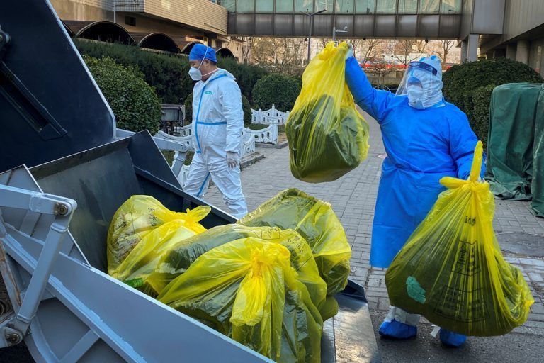 Arbeiter in Schutzanzügen entfernen in Peking Säcke mit Abfall vor einem Gebäude, in dem sich Covid-Infizierte isolieren. Reuters