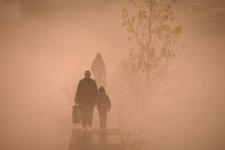 Auf einem Holzsteg: Im dichten Nebel wird dieses Kind in Indien auf seinem Schulweg begleitet. AFP