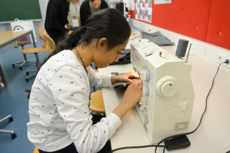 Aya Ibrahim (12) näht konzentriert mit der Maschine an den Tablet-Filzhüllen.