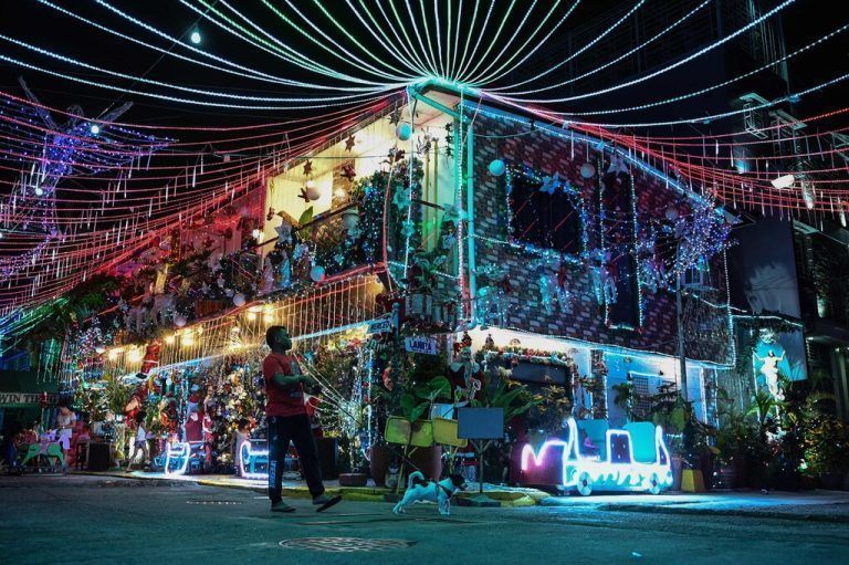 Ein Mann geht mit einem Hund an einem aufwendig weihnachtlich-geschmückten Haus in der philippinischen Hauptstadt Manila vorbei. AFP