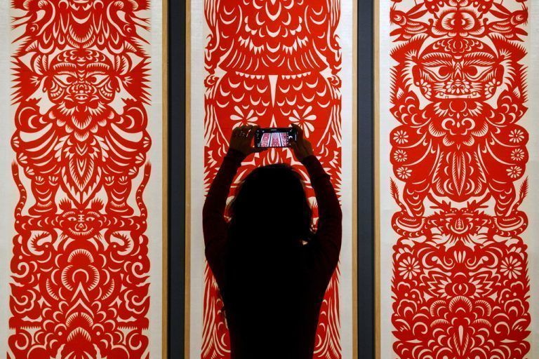 Eine Frau fotografiert traditionelle chinesische Scherenschnittkunst, die in Peking im Kunst- und Handwerksmuseum ausgestellt wird. AP