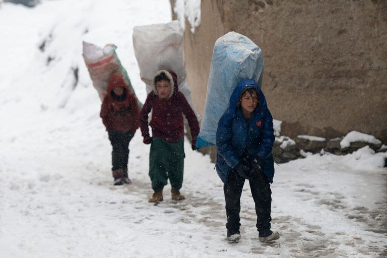 Afghanische Jungen tragen Säcke mit Papiermüll, die sie zum Heizen gesammelt haben, während starken Schneefalls in Kabul. AFP