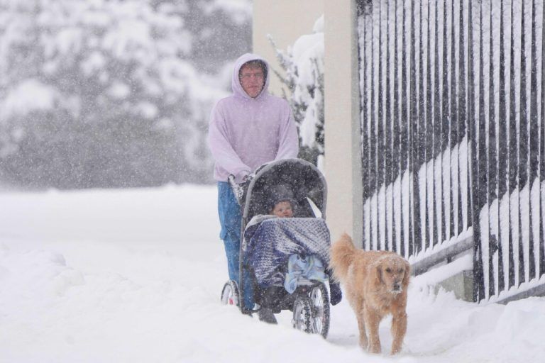 Ein Spaziergänger ist mit Kind und Hund während eines Schneesturms in Provo im US-Staat Utah unterwegs. AFP
