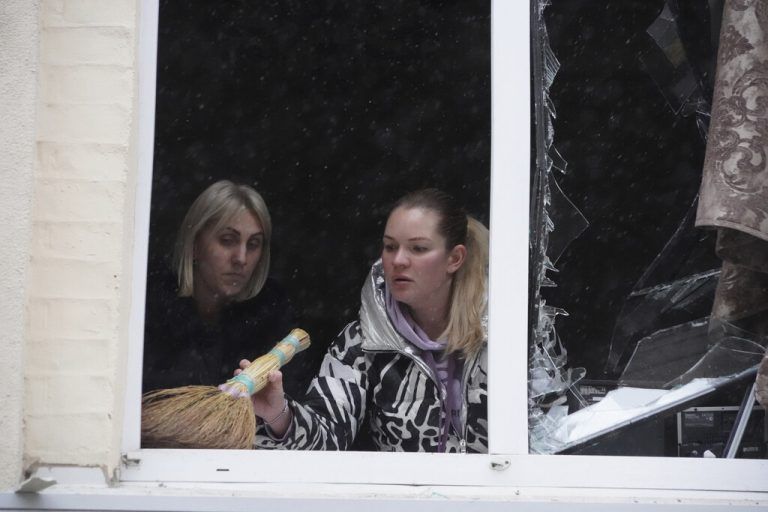 Zwei Frauen entfernen nach einem Raketeneinschlag in Charkiw Scherben.AP