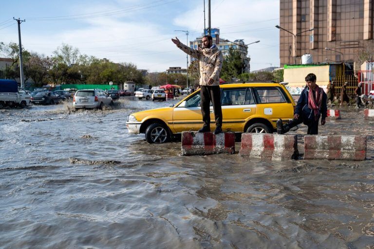 Ein Verkehrspolizist gestikuliert inmitten einer überfluteten Straße in Kabul nach schweren Regenfällen in Afghanistan. AFP