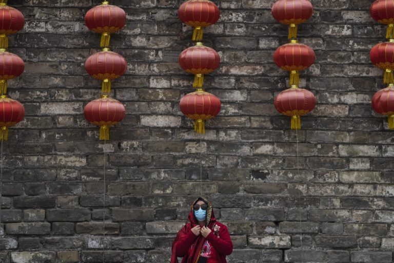 In der chinesischen Hauptstadt Peking rückt eine Frau ihren Schal vor einer Wand mit Laternen zurecht. AP