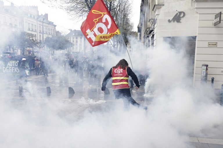 In Frankreich nehmen die Proteste gegen die Rentenreform kein Ende. Ein Mann tritt in Nantes gegen einen Tränengaskanister. AP