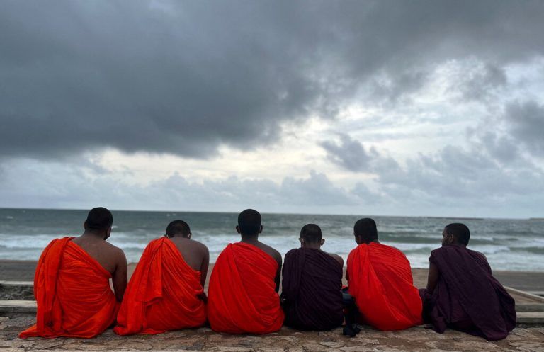 Buddhistische Mönche sitzen an einem Strand in Colombo, Sri Lanka, als sich in der Monsunzeit Regenwolken am Himmel sammeln. Reuters