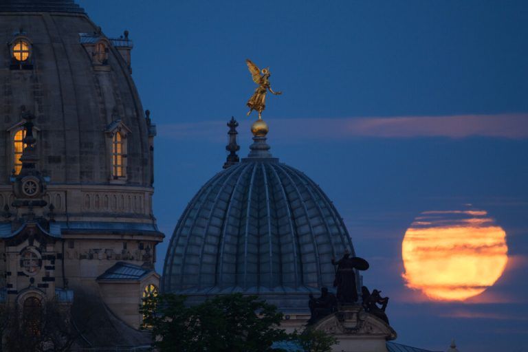 In den frühen Morgenstunden ist der untergehende Mond hinter der Frauenkirche und der Kuppel der Kunstakademie in Dresden zu sehen. APA/DPA