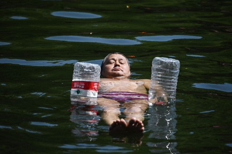 Abkühlung an einem heißen Tag: Mit Wasserflaschen schwimmt dieser Mann in einem Gewässer in der chinesischen Hauptstadt Peking. AFP