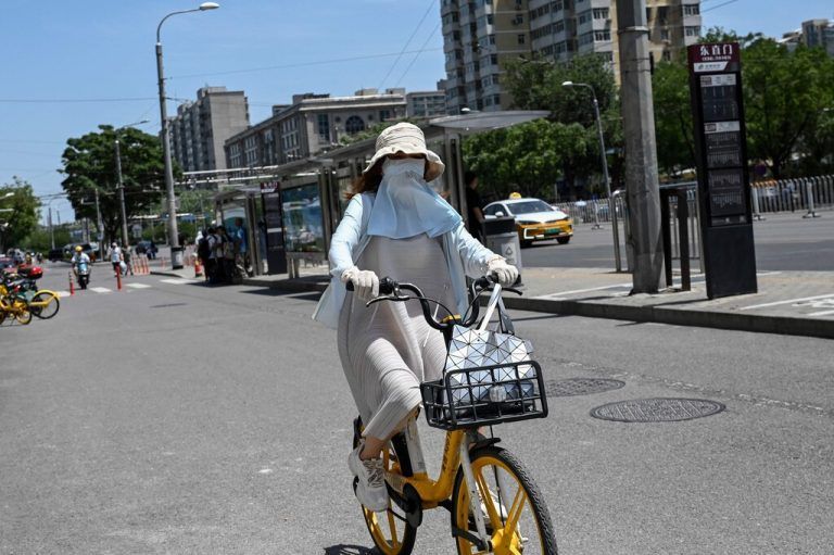 Anhaltende Hitzewelle: Eine Fahrradfahrerin in der chinesischen Hauptstadt Peking versucht sich vor der Sonne zu schützen. AFP