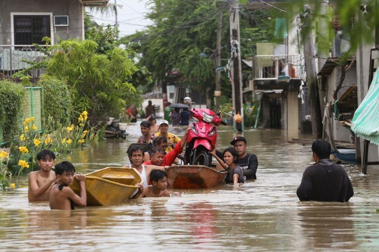 Anwohner in der Provinz Bulacan in Thailand transportieren ein Motorrad auf einem Boot, da die Straßen nach den sintflutartigen Regenfällen des Taifuns Doksuri überschwemmt sind. AFP