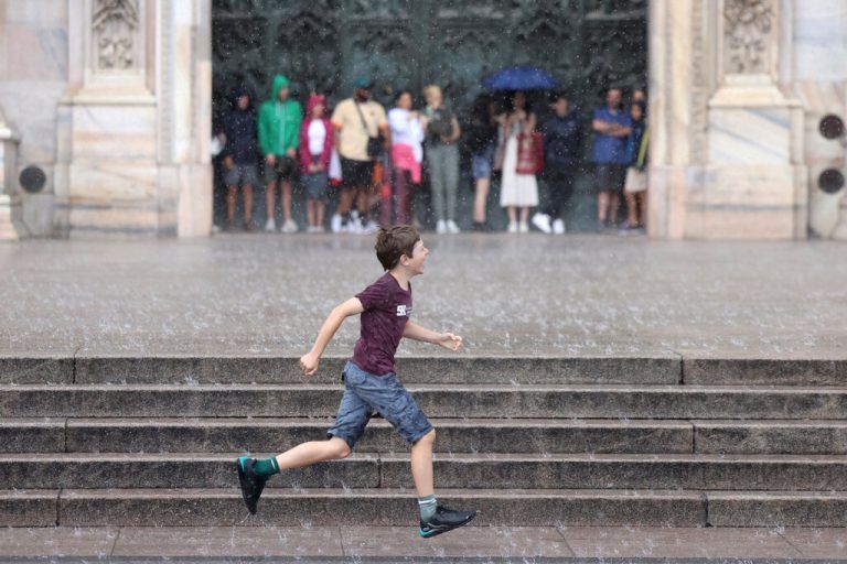 Beim Dom in Mailand rennt ein Junge durch den Regen, während eine Touristengruppe im Hintergrund Schutz im Trockenen sucht. Reuters