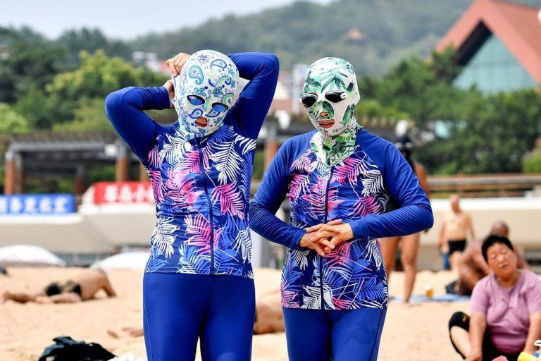 Etwas anderer Sonnenschutz: Mit Facekini entspannen sich diese Frauen an einem Strand in Qingdao in der chinesischen Provinz Shandong. AFP