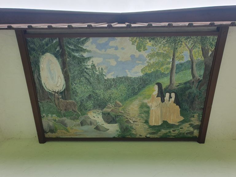 Die Begegnung mit der Gottesmutter im Geweih ist an der Decke am Eingang der Kapelle verewigt. Dieser mystische Hirsch soll sie bis zur Anhöhe geführt haben, auf der später das Kloster Hirschthal errichtet wurde.