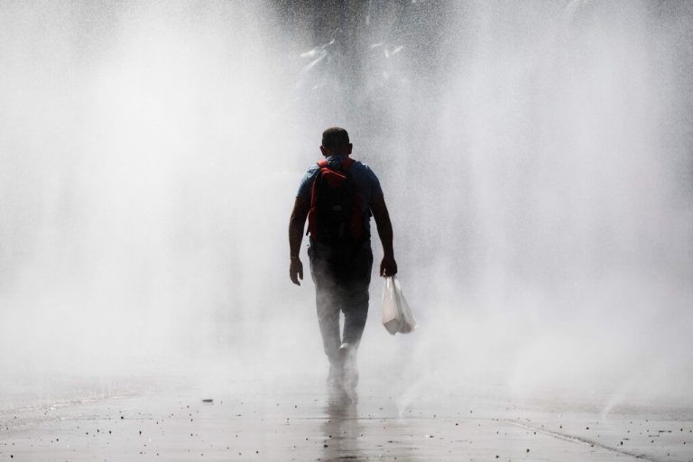 Bei Temperaturen von knapp 35 Grad geht ein Mann durch das Wasserspiel am Wiener Praterstern. AFP