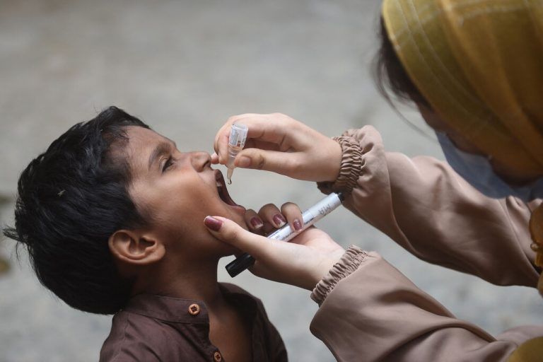 In der pakistanischen Großstadt Karatschi wird ein Kind bei einer Tür-zu-Tür-Impfaktion gegen die Kinderlähmung geschützt. AFP