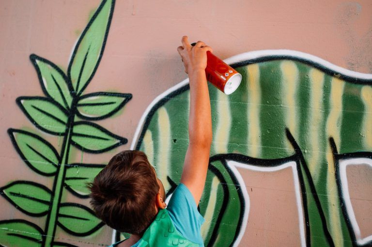 Kinder entdecken die Welt der Graffiti-Kunst und verwandeln triste Wände in bunte Kunstwerke.