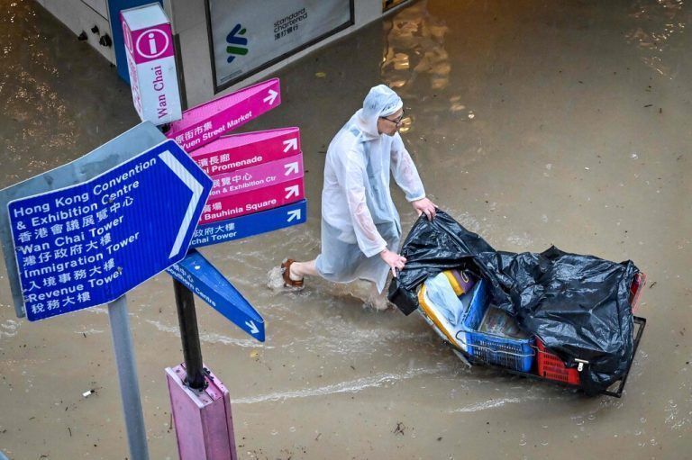 Ein Mann schiebt einen Karren über eine überflutetn Straße in Hongkong. Rekordniederschläge führten zu großflächigen Überschwemmungen. AFP