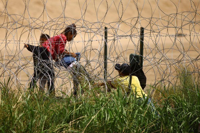 Migranten überwinden am Ufer des Rio Bravo, der Grenze zwischen den USA und Mexiko, einen Stacheldrahtzaun. Reuters
