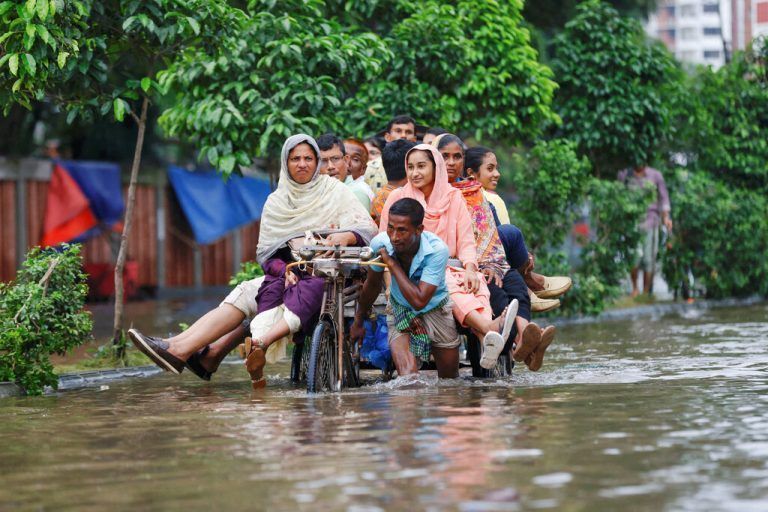 Pendler fahren nach heftigen Regenfällen in Dhaka, Bangladesch, mit einer Rikscha auf einer überschwemmten Straße. reuters