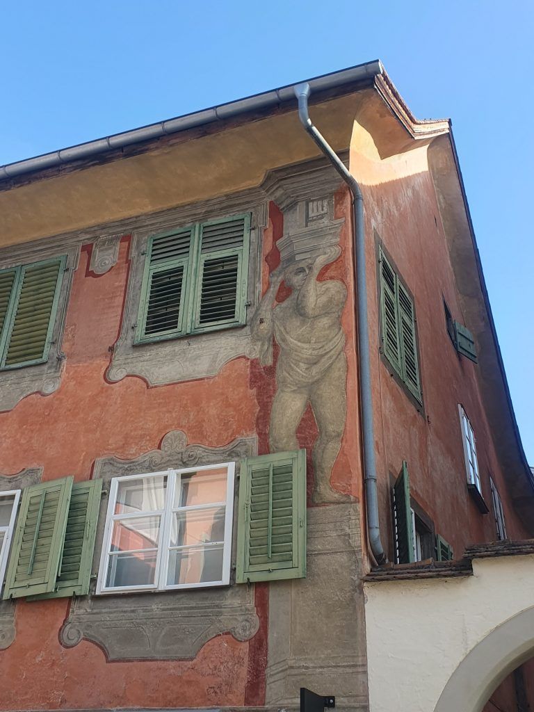 Wandmalereien und die grünen Fensterläden runden das optische Gesamtbild ab.