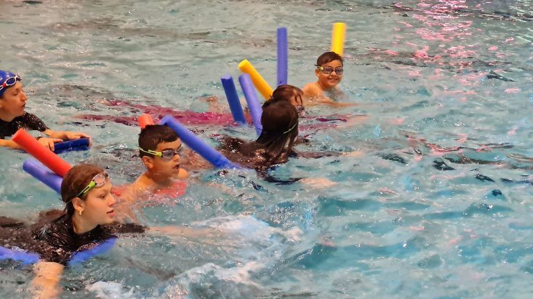 Gruppenübung im Becken: Gemeinschaftsgefühl beim Schwimmlernen.
