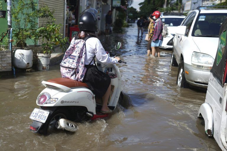 Nach den jüngsten Regenfällen fährt eine Person mit dem Motorrad über eine überflutete Straße in der Innenstadt von Phnom Penh, Kambodscha. AP