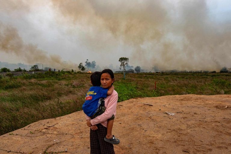Während die Feuerwehr versucht, einen Torfbrand in der Nähe ihres Hauses in Palembang auf Sumatra zu löschen, hält ein Mädchen ihren kleinen Bruder im Arm. AFP