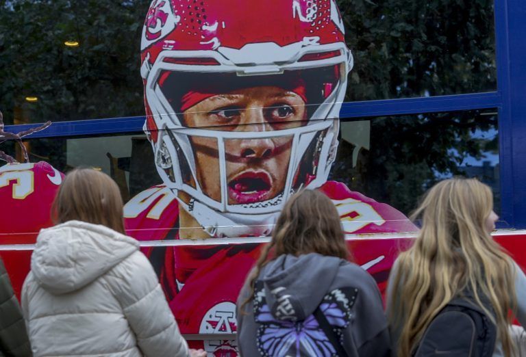 Fans in Frankfurt vor dem überdimensionalen Werbeplakat mit Chiefs-Quarterback Patrick Mahomes.ap