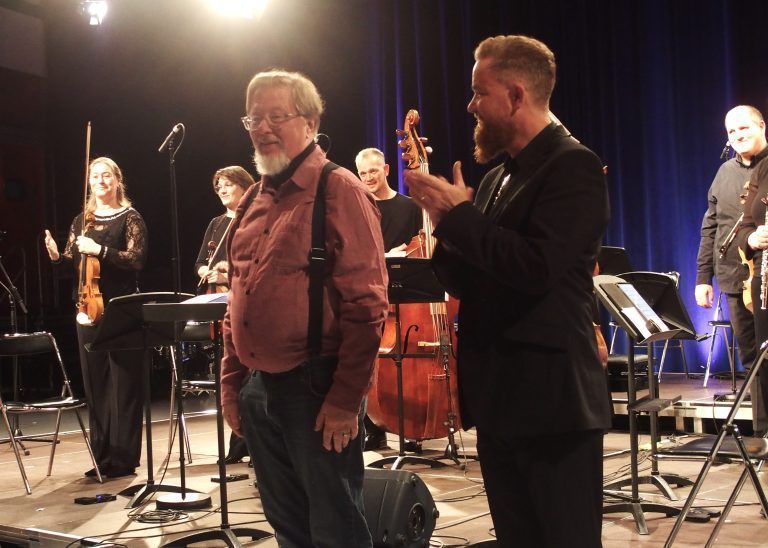 Der Komponist Georg Friedrich Haas links mit dem Dirigenten Thomas Gertner und Musikern im Applaus.
