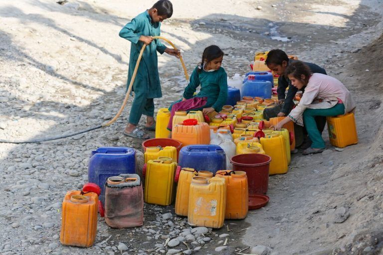 Am Rand einer Straße in Jalalabad, Afghanistan, befüllen Kinder Kanister mit Trinkwasser. AFP