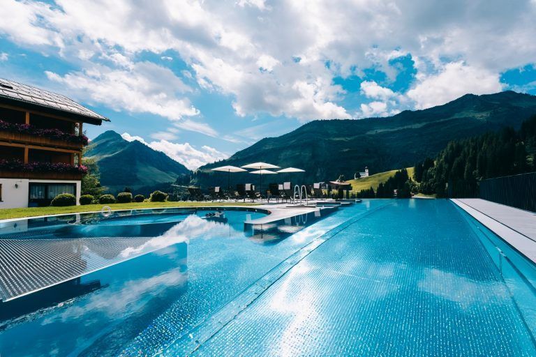 Eine exklusive Attraktion bietet die Damülser Alpenblume mit dem neuen Freischwimmbecken einschließlich Lazy Riverpool mit Blick auf das Bergpanorama samt Damülser Kirche.